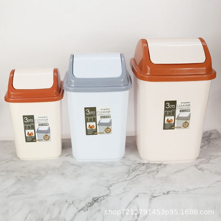 Three plastic 3-liter kitchen trash cans in different sizes, displayed on a white marble surface against a white wall. The trash cans have cream-colored bodies, orange lids, and labels on the front.