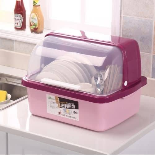 A pink and purple plastic dish rack with a clear lid, shown on a kitchen counter with white plates inside.