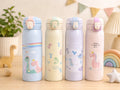 Four colorful thermos bottles with dinosaur illustrations on a wooden surface.