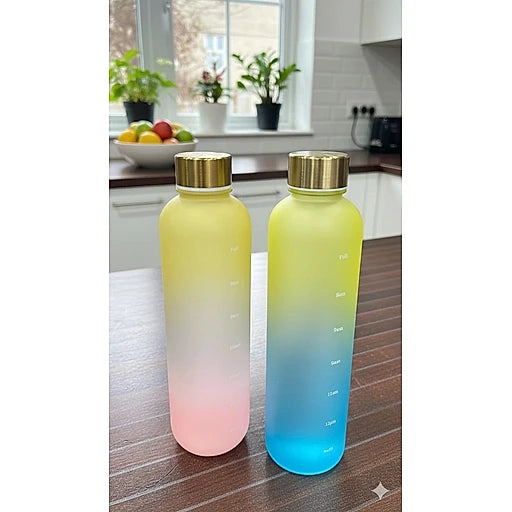 Two gradient water bottles on a kitchen counter with fruits and plants in the background.