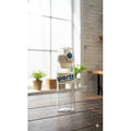 Clear water bottle with 'sports' text on a wooden table near a window.