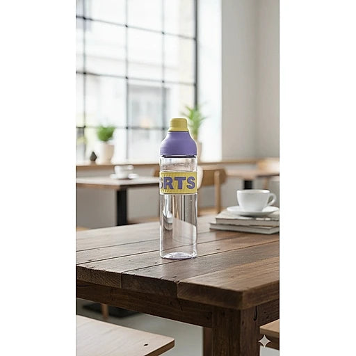 Clear bottle with a purple label on a wooden table in a room with large windows.