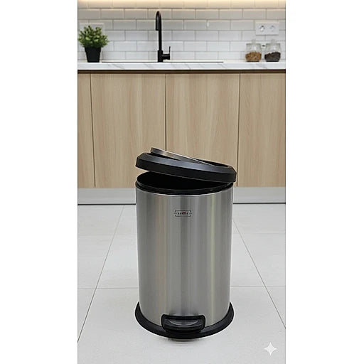 Stainless steel trash can in a kitchen setting with wooden cabinets and a white tiled floor.
