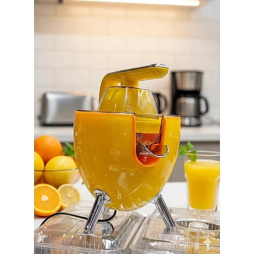Yellow manual juicer with oranges and a glass of juice in a kitchen setting