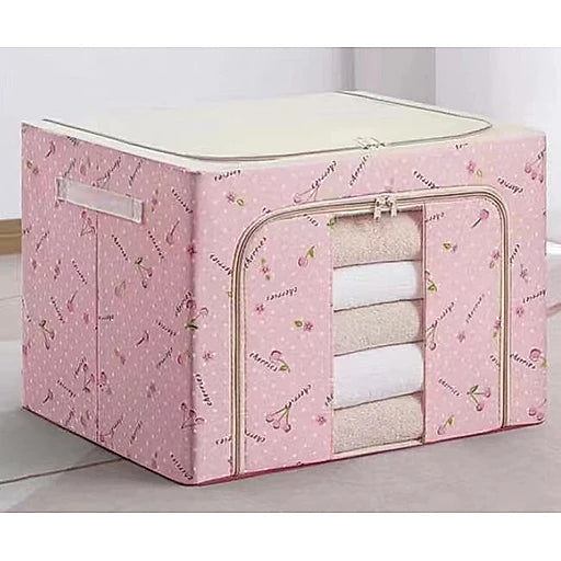 Pink storage cube with floral pattern containing folded clothes on a light background