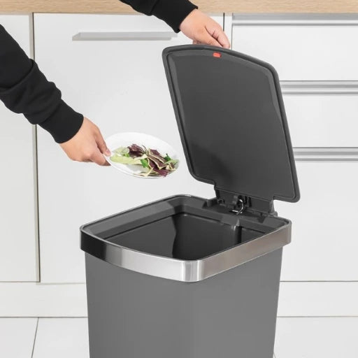 Person disposing of food waste into a kitchen compost bin.